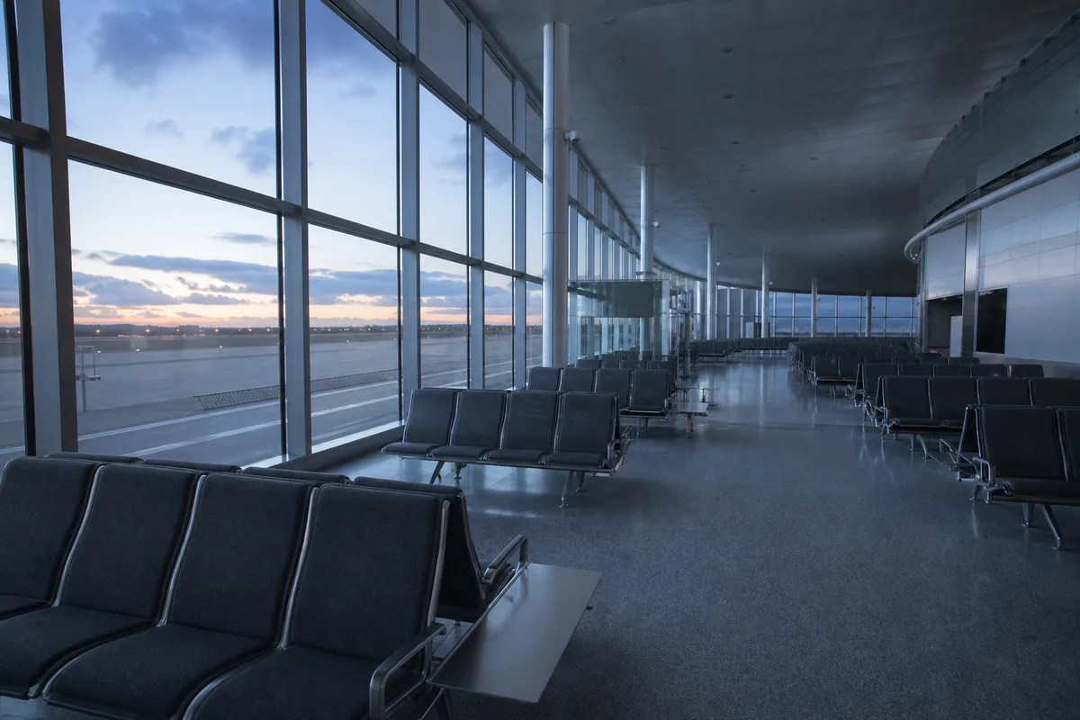 Salle d&rsquo;attente d&rsquo;aéroport déserte au petit matin, rangées de sièges vides